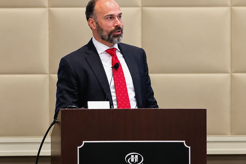 David Abayev speaking at a Hilton Anatole podium at the AAID Annual Conference in Dallas